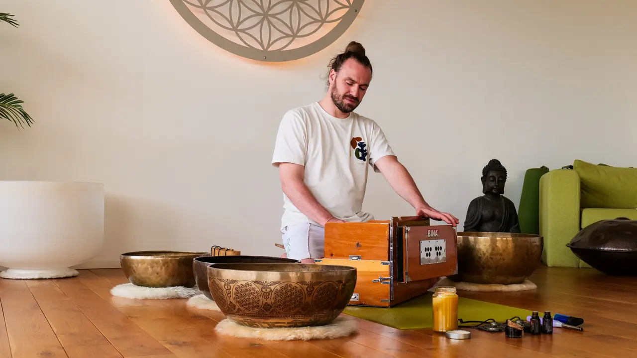 Michi Willkommen spielt Harmonium, vor ihm mehrere Klangschalen auf dem Holzboden.